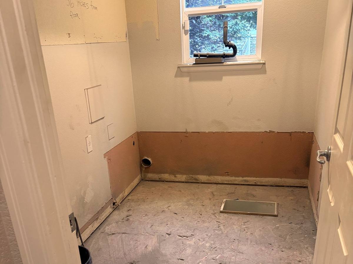 Laundry room stripped to the subfloor after demolition