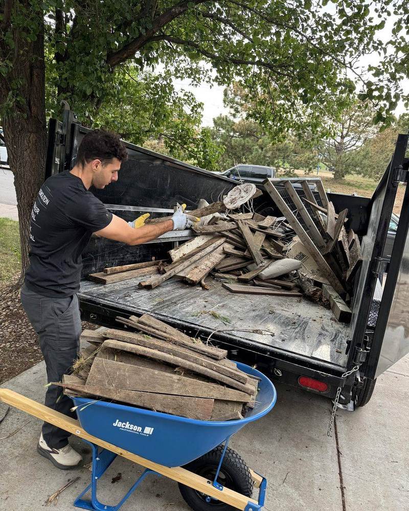 Mayer Enterprises crew member loading debris into the dump trailer in Denver