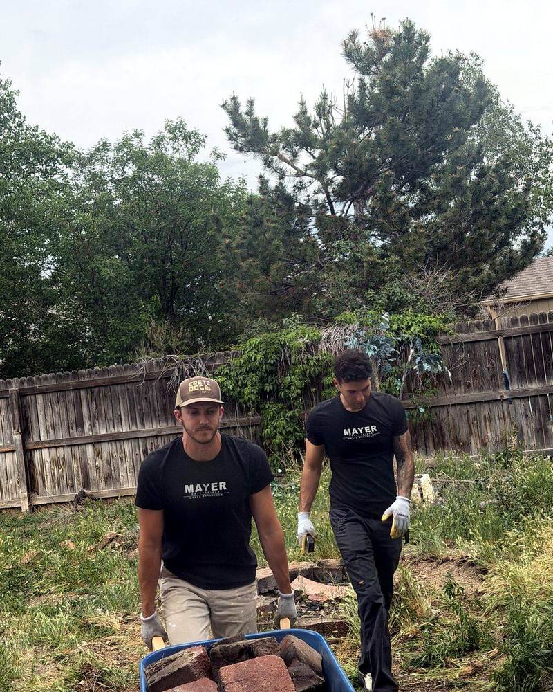 Mayer Enterprises crew hauling debris with a wheelbarrow on a Denver junk removal job
