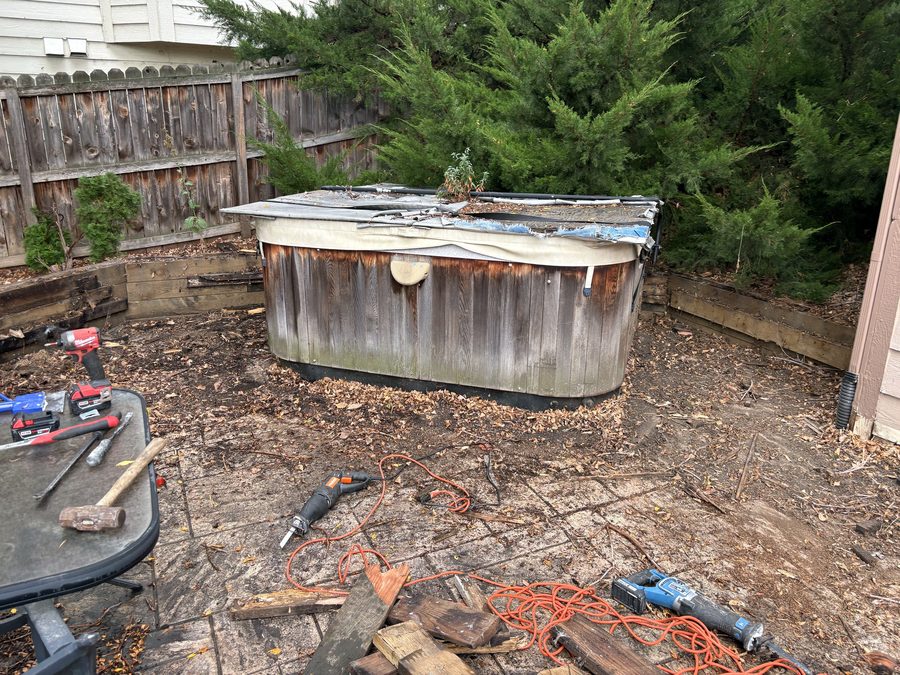 Deck boards pulled and tools staged during a deck and hot tub demolition in Arvada, Colorado