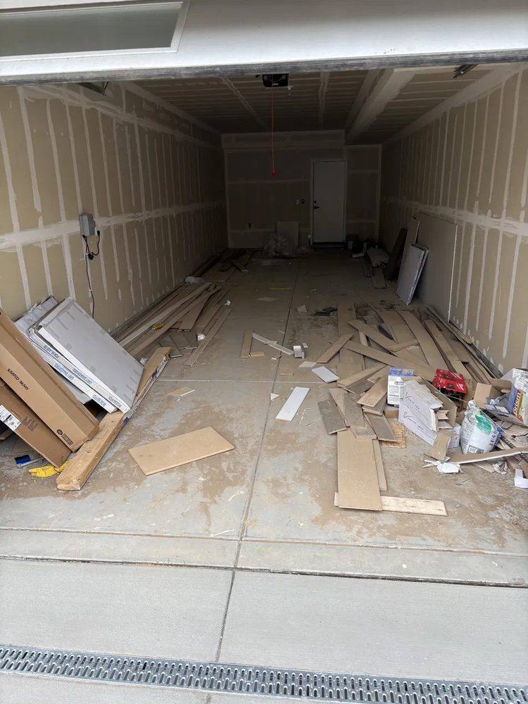 Garage full of leftover construction and flooring debris in Denver before cleanout
