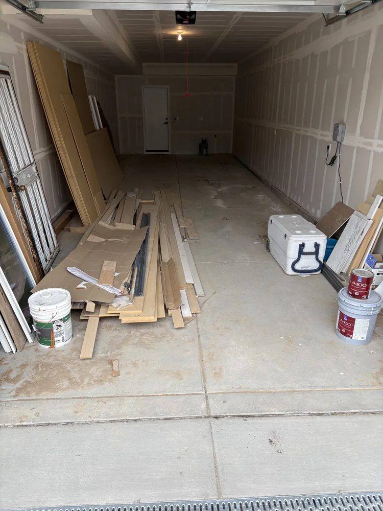 Garage with leftover lumber, cardboard, and paint buckets in Denver before cleanout